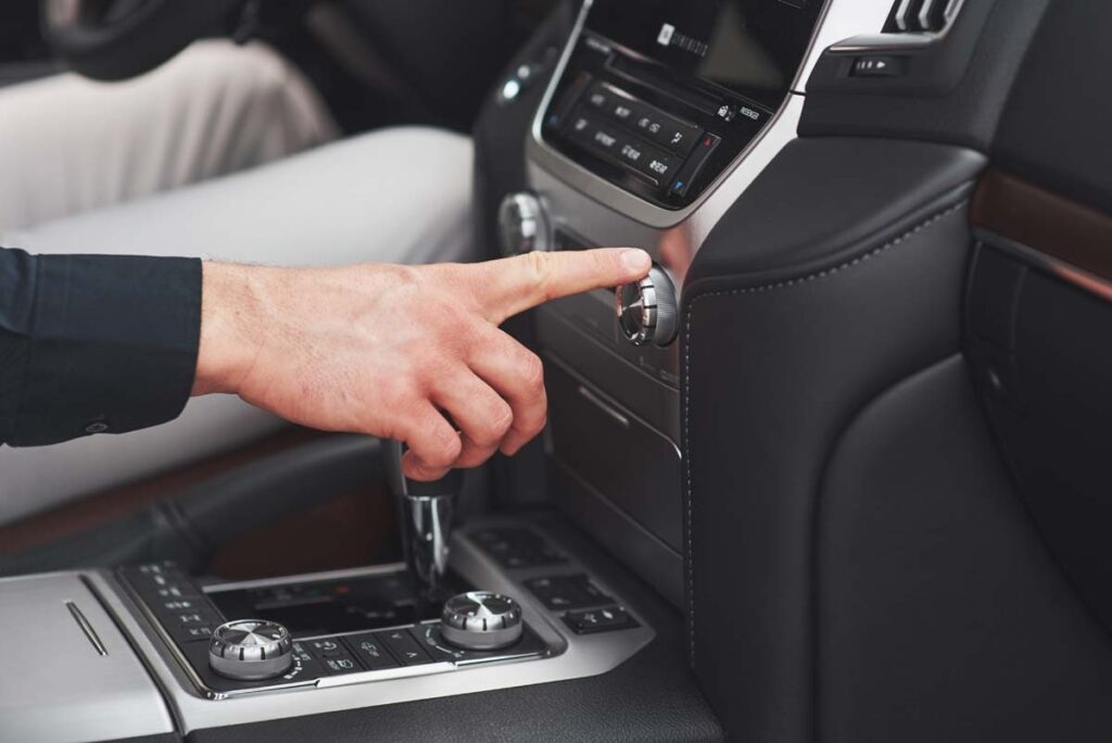 Main réglant une commande sur la console centrale d’une voiture.
