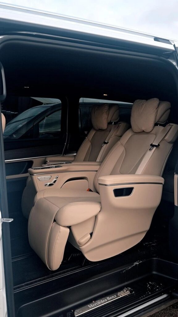 Fauteuils individuels beiges avec accoudoirs et repose-jambes dans un van.