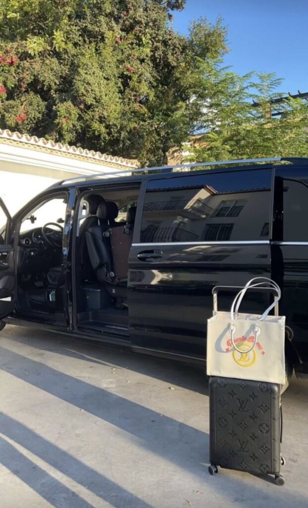 Van noir avec la porte coulissante ouverte et des bagages posés à côté.