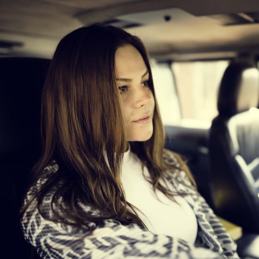 Femme assise à l’arrière d’une voiture.