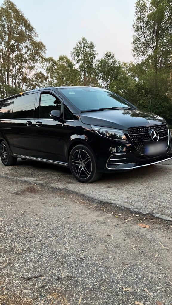 Van Mercedes noir stationné devant des arbres.