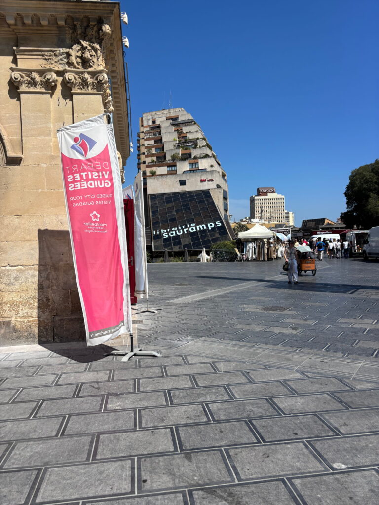 Place piétonne devant un office de tourisme sous un ciel bleu.